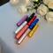 Group of eight reusable aromatherapy inhalers in various colors on white tablecloth with wedding roses and candle in the background